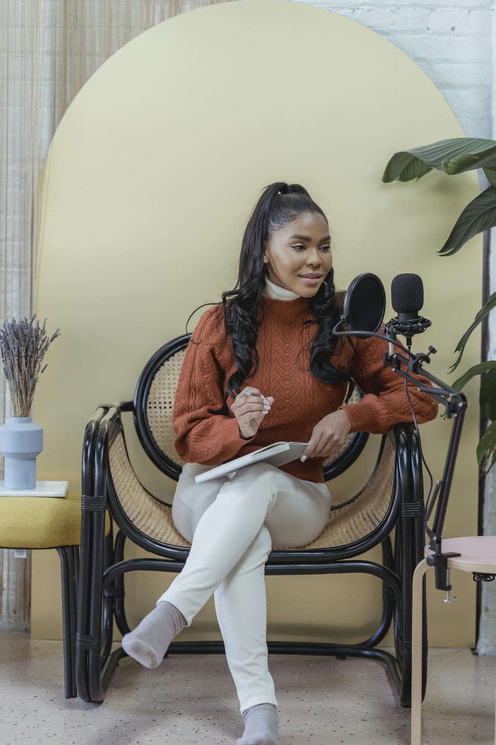 Positive ethnic female podcaster speaking into microphone